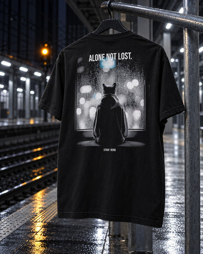 Alone Not Lost Tee Cinematic, back print, black, hanging on a railing on a wet train platform at night — AI-generated visual