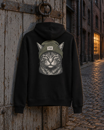 Beanie Cat Hoodie Shade, back print, black, hanging on a weathered wooden door in a cobbled lane at night — AI-generated visual