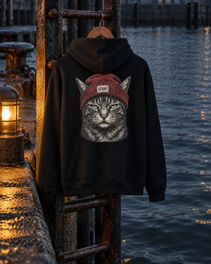 Beanie Cat Hoodie Rogue, back print, black, hanging on a rusted ladder at the harbour wall beside a lantern at night — AI-generated visual