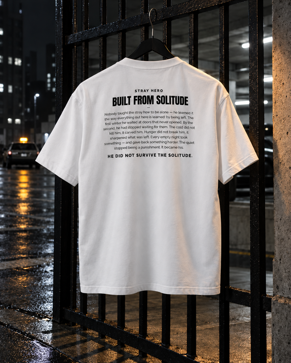 Built From Solitude Story Tee White, back print, white, hanging on a metal gate at night — AI-generated visual