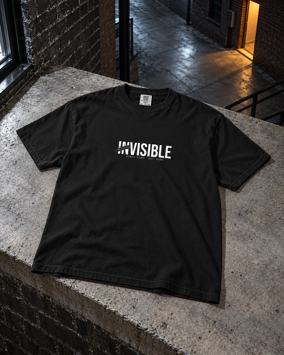 Invisible Tee, front print, black, laid on a stone ledge in a courtyard at night — AI-generated visual