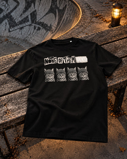 None of Them Talked Tee, front print, black, laid on a wooden bench at a skatepark under a lantern at night — AI-generated visual