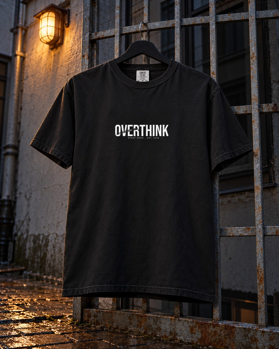 Overthink Tee, front print, black, hanging on rusted iron bars in a rainy backyard at night — AI-generated visual