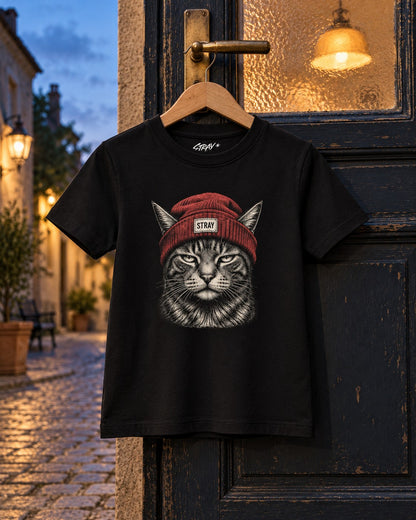 Rogue Kids Tee, front print, black, hanging on an old door under a glass lamp at dusk — AI-generated visual