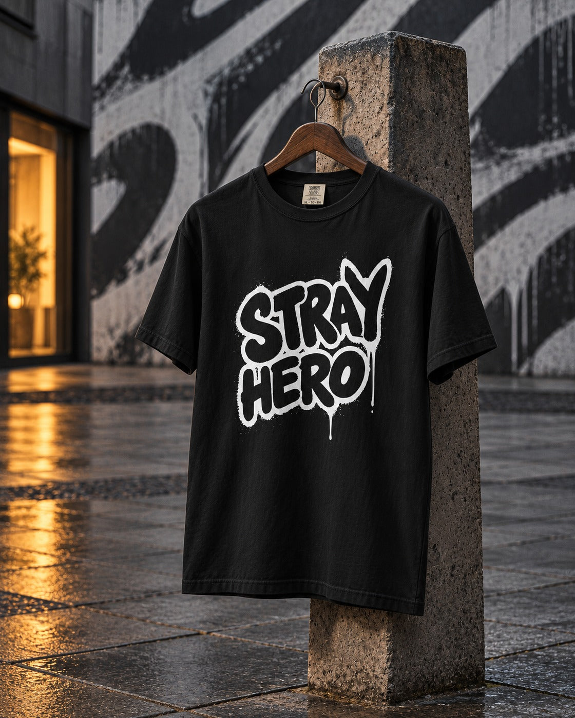 Spray Tag Tee, front print, black, hanging on a concrete post in front of a graffiti wall at night — AI-generated visual
