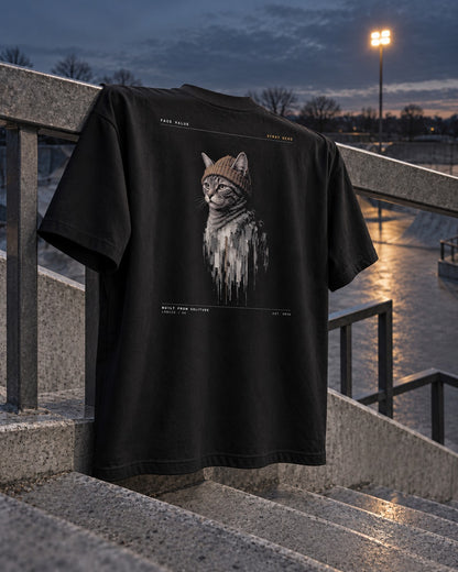 Still Wet Oversized Tee, back print, black, hanging on a skatepark stair railing under floodlights at dusk — AI-generated visual