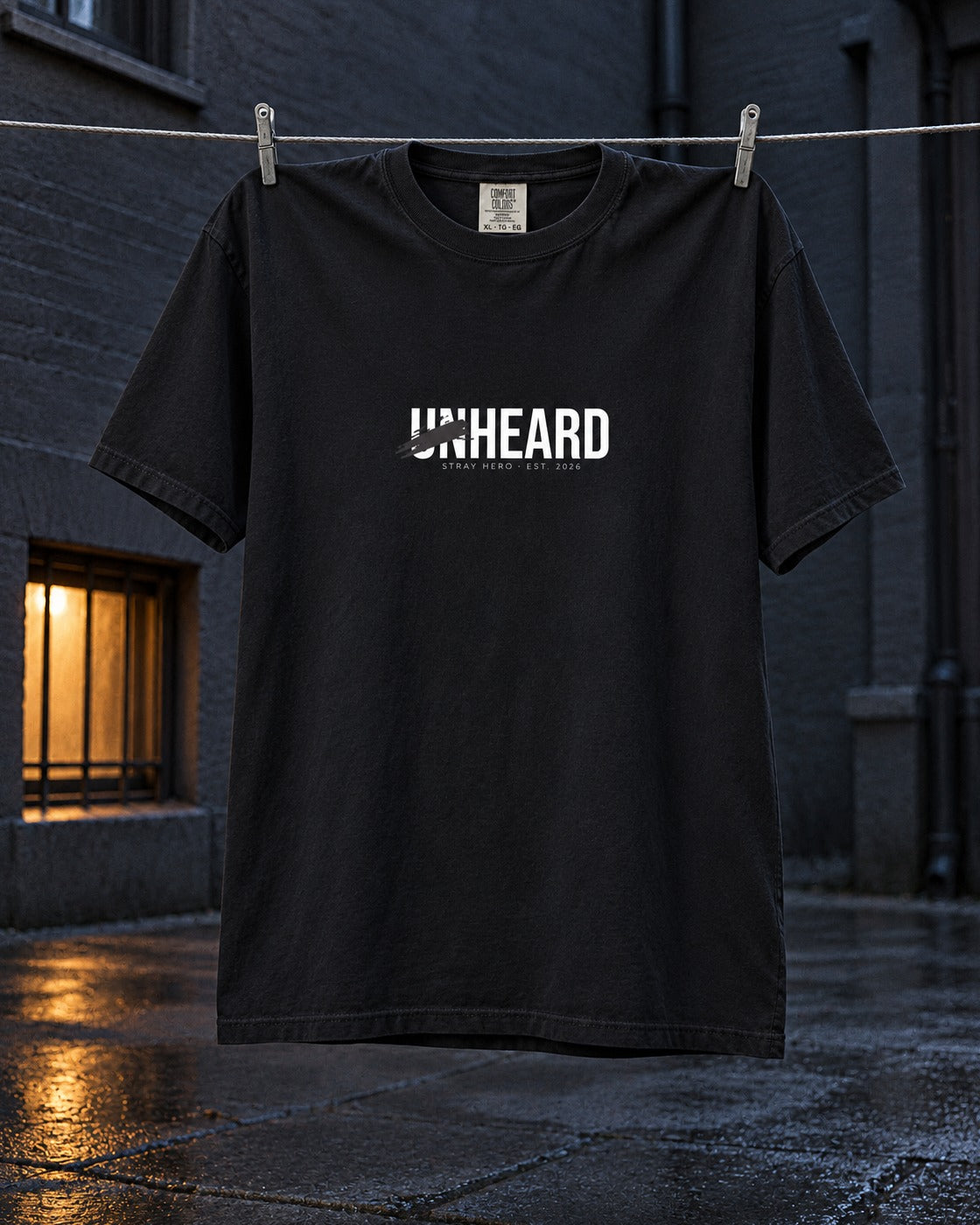 Unheard Tee, front print, black, pegged on a clothesline in a dark backyard at night — AI-generated visual