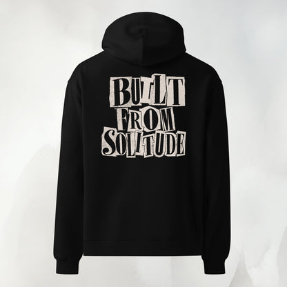 Back print of the Built From Solitude paste-up hoodie in black: hand-cut letters stacked into the words BUILT FROM SOLITUDE