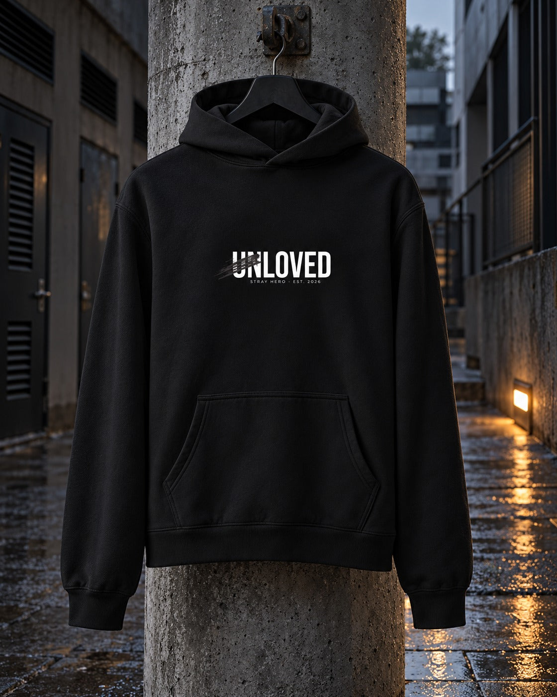 Unloved Hoodie, front print, black, hanging on a concrete pillar in a wet passageway at night — AI-generated visual